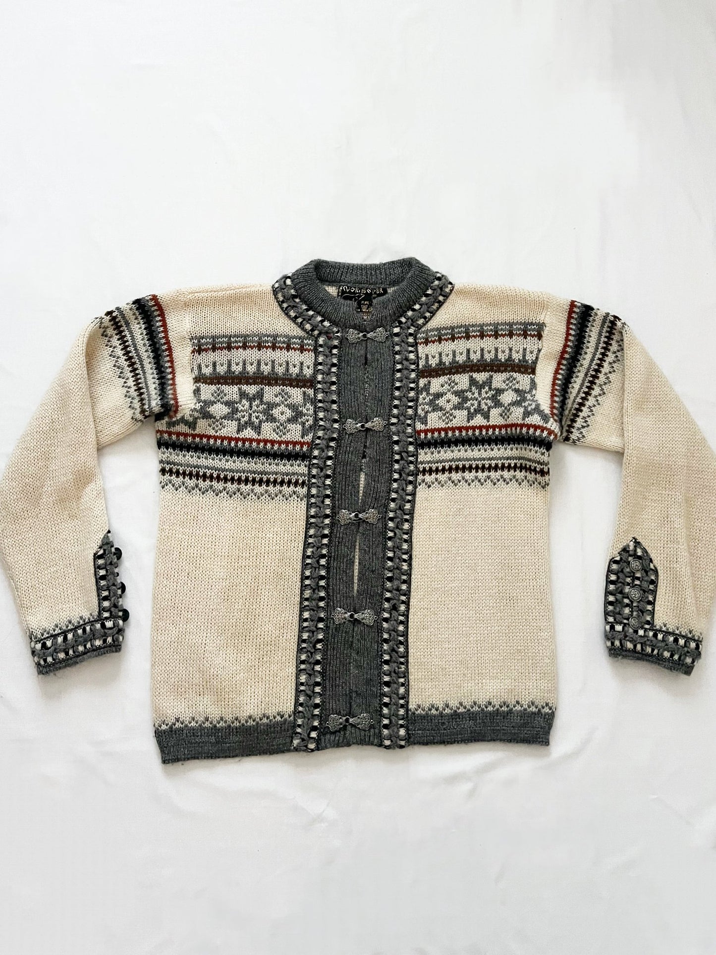 A wool cardigan in a classic Nordic/Norweigan pattern, mainly in gray and white. Has buttons on the sleeves. Made in Norway.