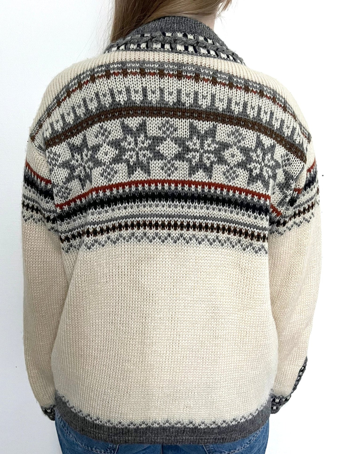 A wool cardigan in a classic Nordic/Norweigan pattern, mainly in gray and white. Has buttons on the sleeves. Made in Norway.