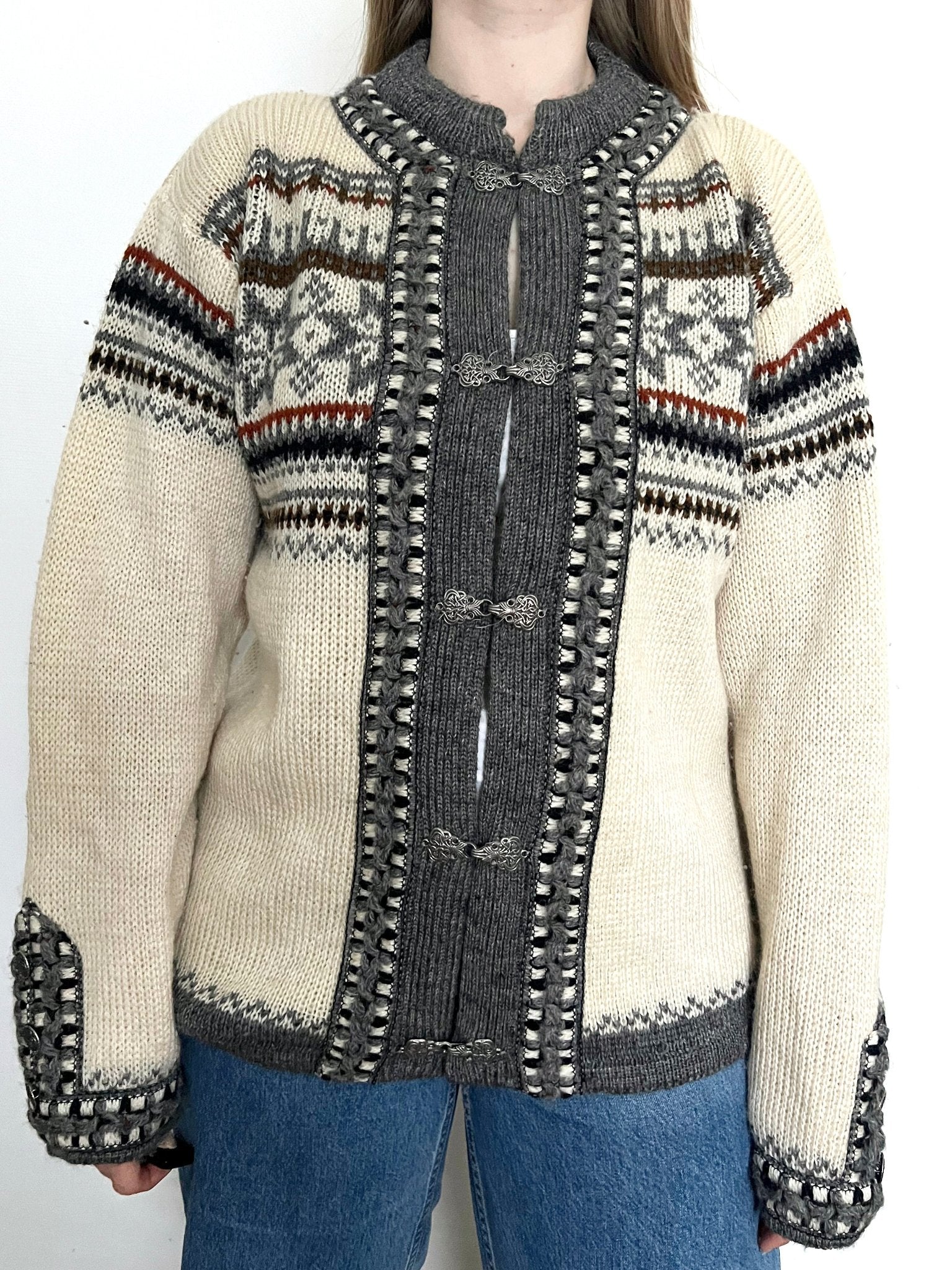 A wool cardigan in a classic Nordic/Norweigan pattern, mainly in gray and white. Has buttons on the sleeves. Made in Norway.