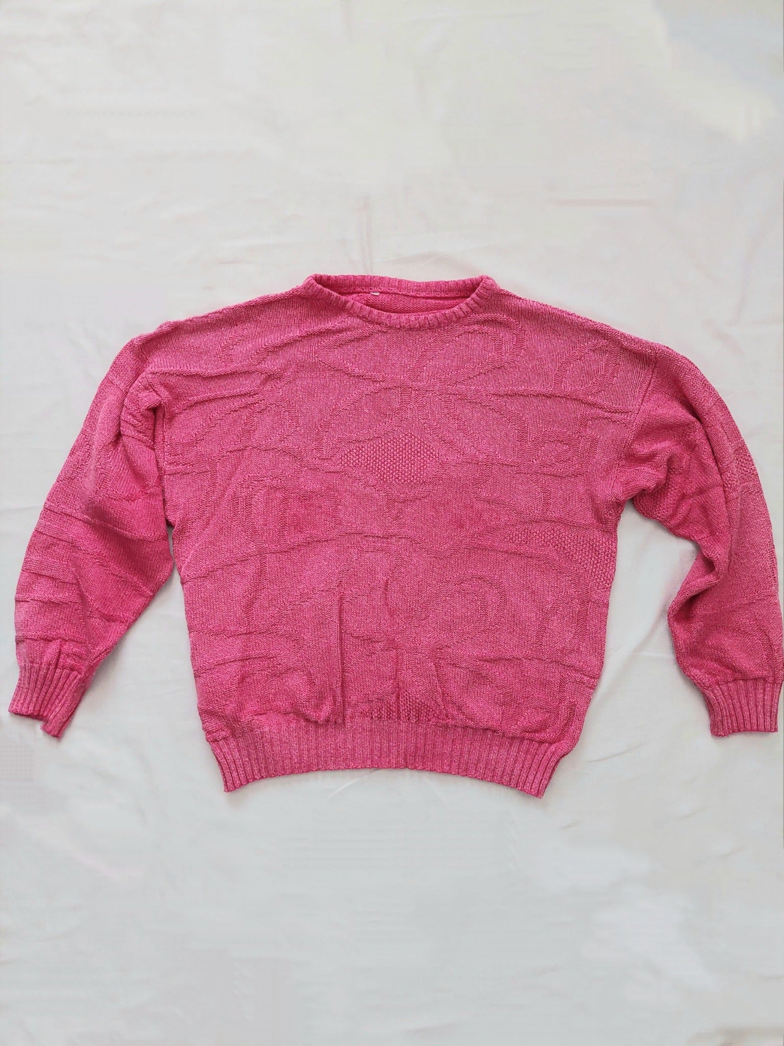 A pink knitted sweater with unique swirly pattern 