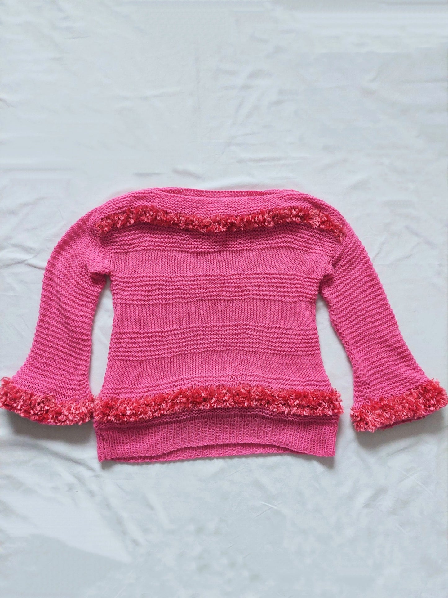 A pink sweater with fluffy details, three-quarter lenght sleeves and a boat neck