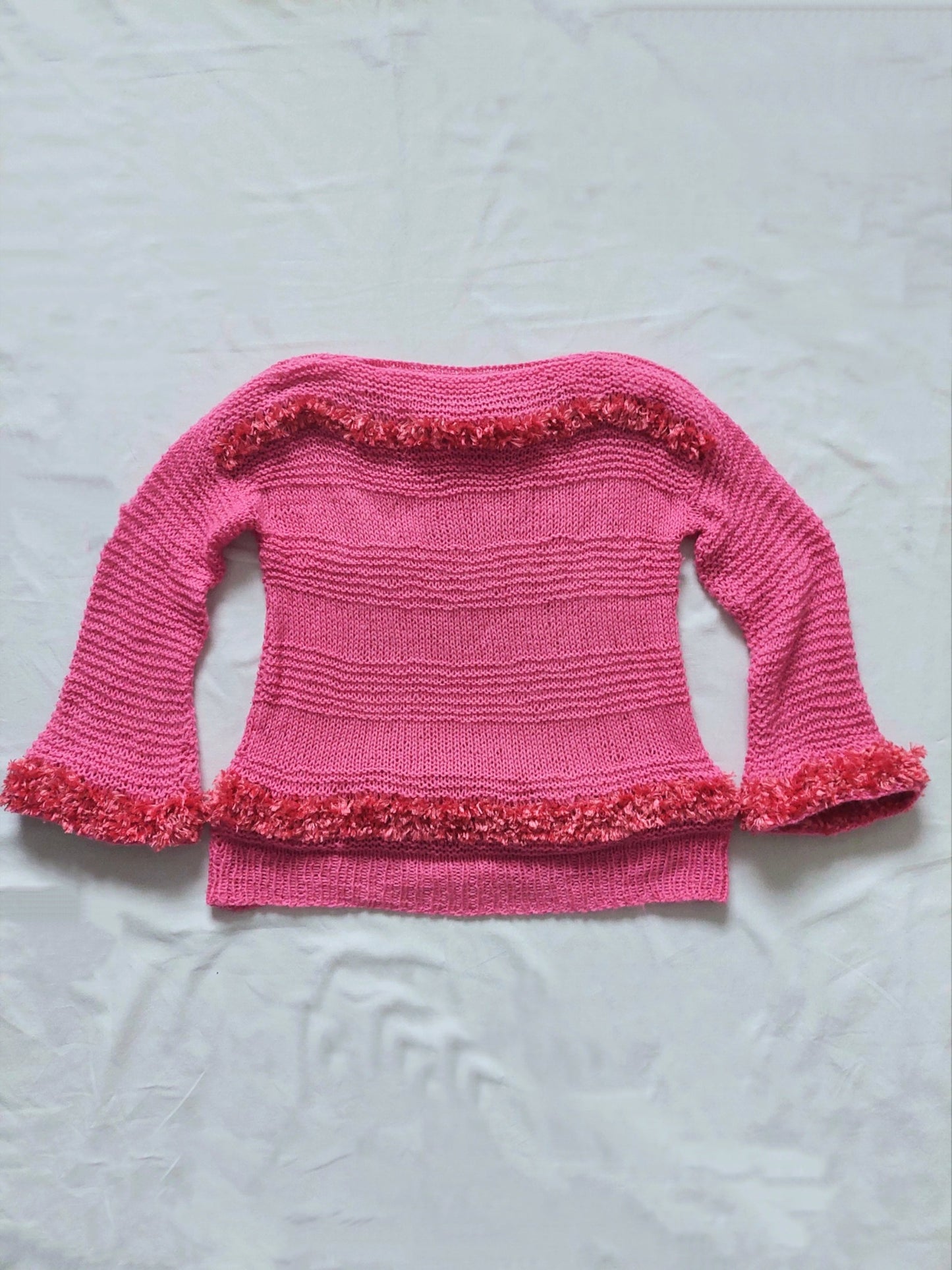 A pink sweater with fluffy details, three-quarter lenght sleeves and a boat neck