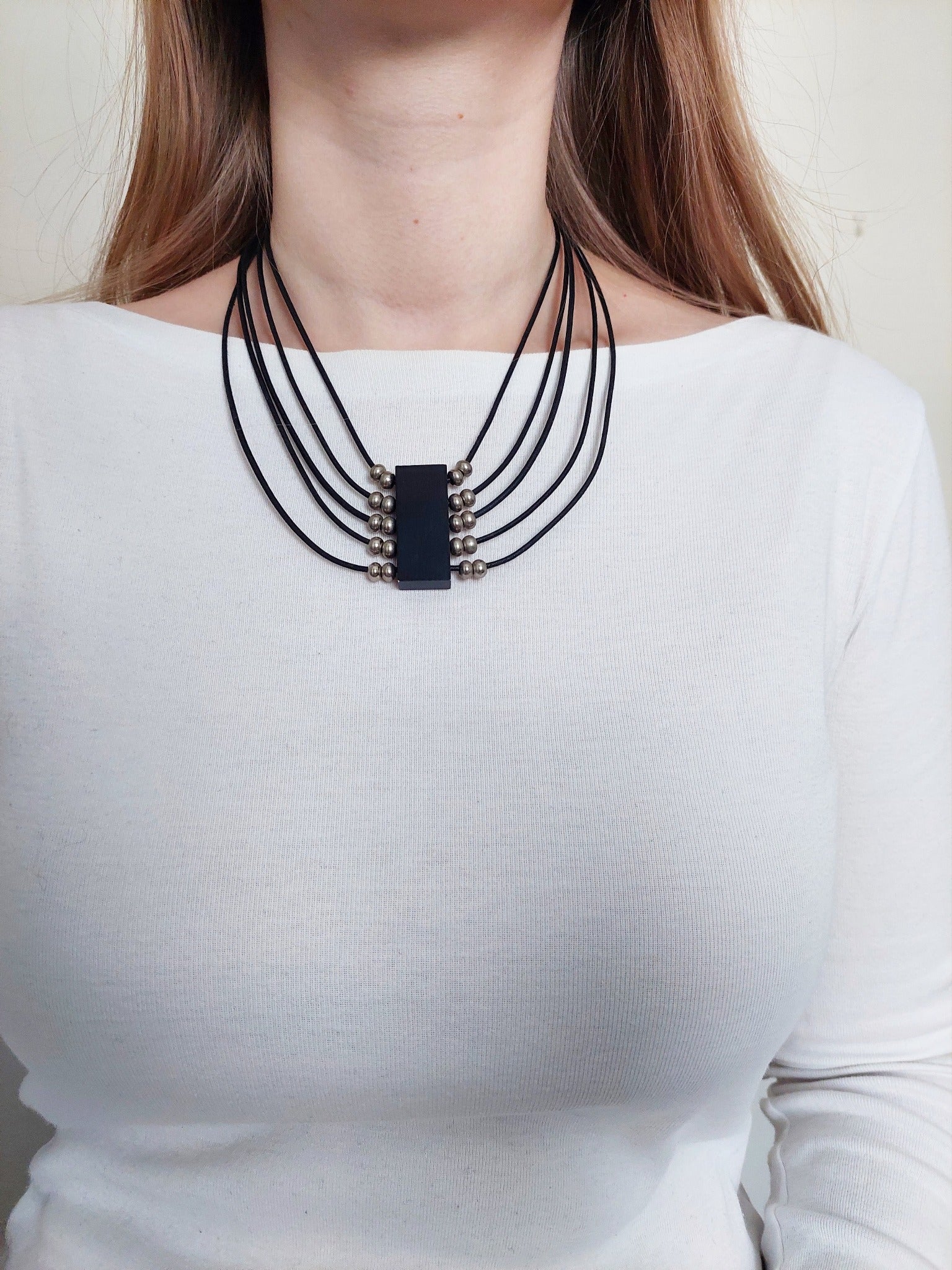 A black necklace  with a black woodpiece, and metal details 