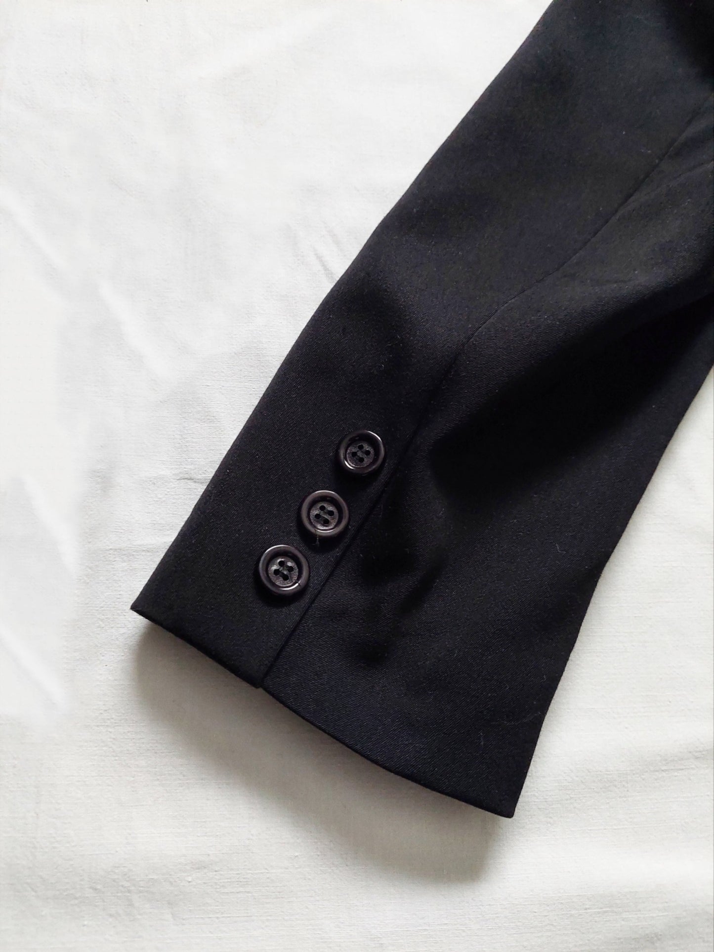 Close up of 3 buttons on the sleeve of the black suit