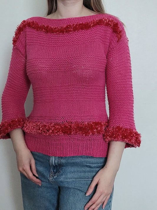 A person wearing the pink sweater with fluffy details, three-quarter lenght sleeves and a boat neck