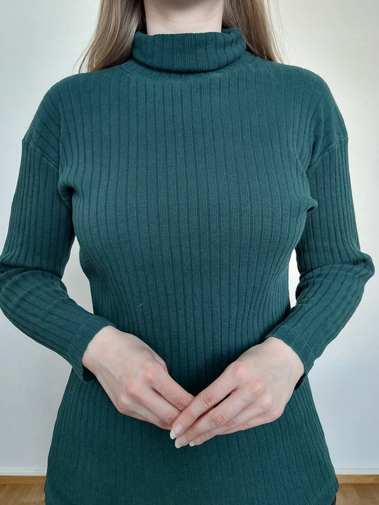 A person wearing the green ribbed turtleneck