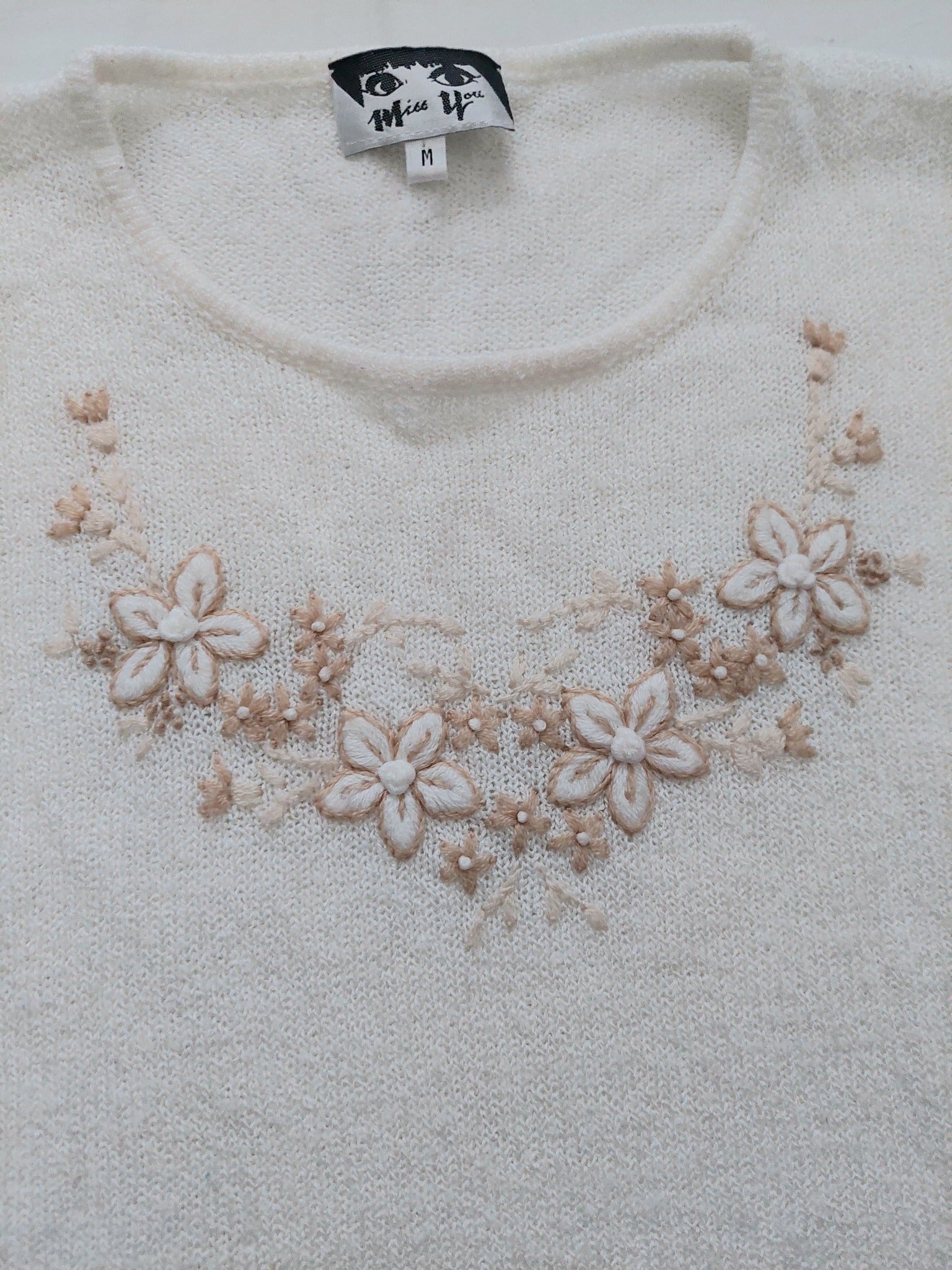 A close up of the white flower sweater